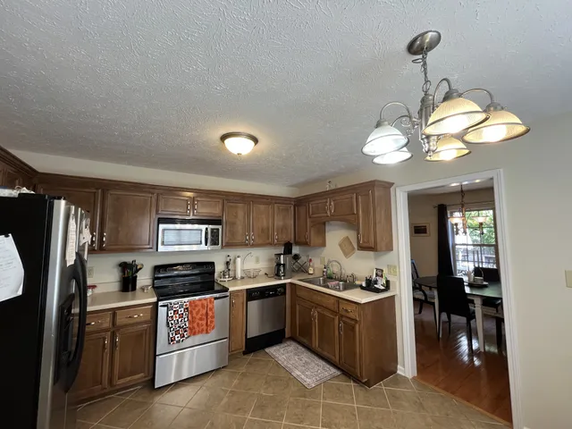 a kitchen with a refrigerator a stove a sink a dining table and chairs