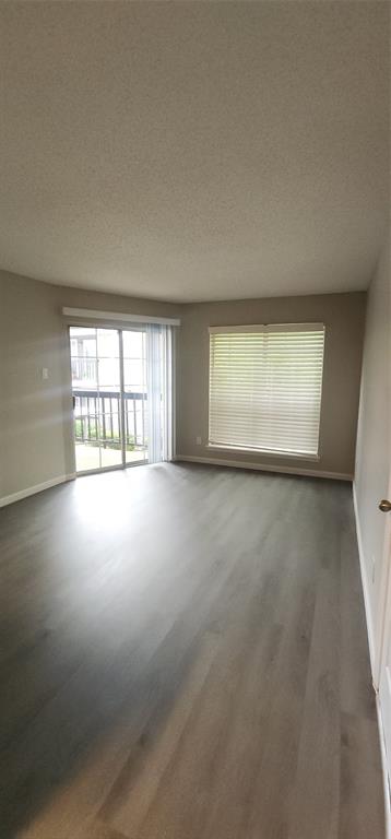 18333 Roehampton Drive, Unit 927 Dallas, TX 75252 - Photo 11 of 26 Spare room featuring wood finished floors and a textured ceiling