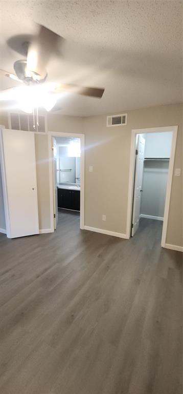 18333 Roehampton Drive, Unit 927 Dallas, TX 75252 - Photo 15 of 26 Empty room with ceiling fan, dark wood-type flooring, and a textured ceiling