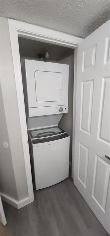 18333 Roehampton Drive, Unit 927 Dallas, TX 75252 - Photo 17 of 26 Laundry room with estacked washer and dryer, a textured ceiling, and wood finished floors