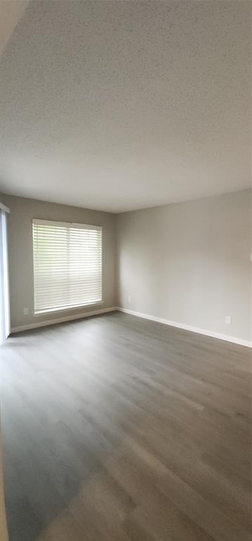 18333 Roehampton Drive, Unit 927 Dallas, TX 75252 - Photo 21 of 26 Empty room featuring wood finished floors and a textured ceiling