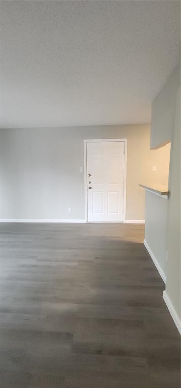 18333 Roehampton Drive, Unit 927 Dallas, TX 75252 - Photo 22 of 26 Spare room with dark wood-type flooring and a textured ceiling