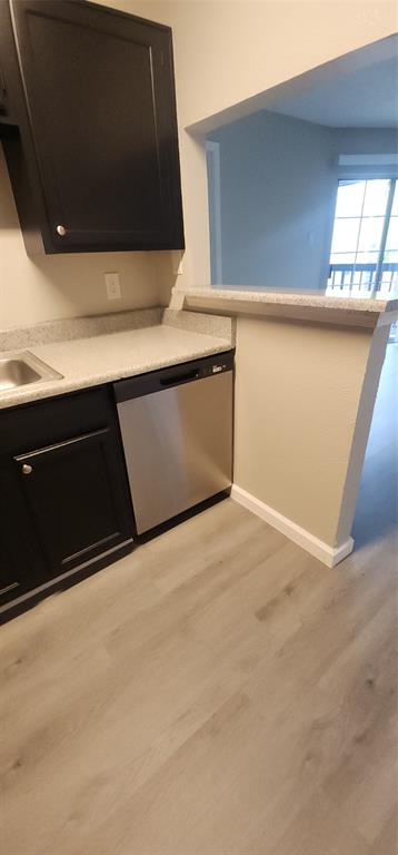 18333 Roehampton Drive, Unit 927 Dallas, TX 75252 - Photo 9 of 26 Kitchen featuring stainless steel dishwasher, light wood-type flooring, dark cabinets, and light countertops