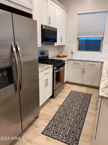 a kitchen with stainless steel appliances granite countertop a refrigerator and a stove top oven