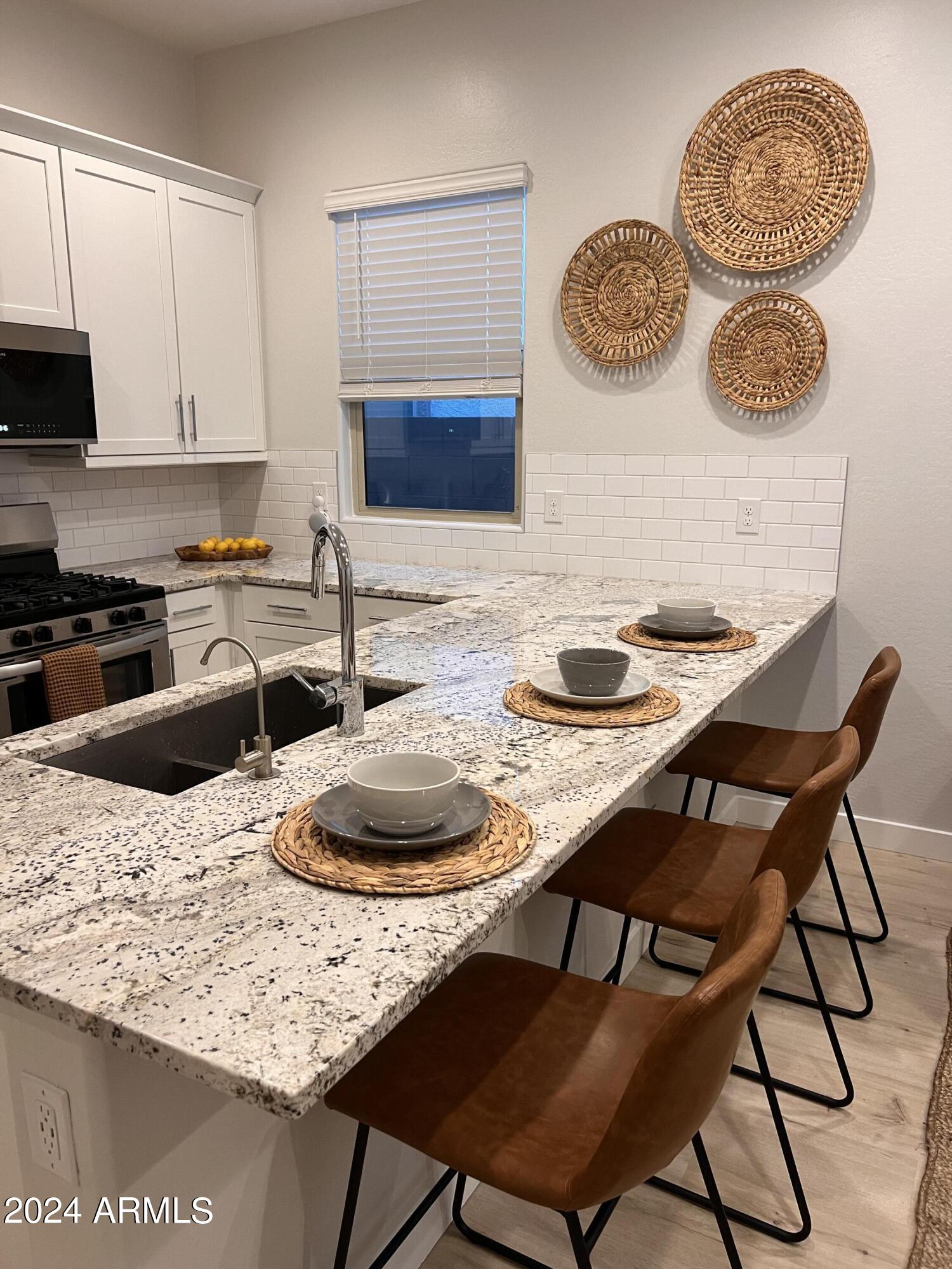 9749 East Tahoe Avenue, Unit 2 Mesa, AZ 85212 - Photo 8 of 25 a kitchen with a table chairs and a stove top oven with wooden floor