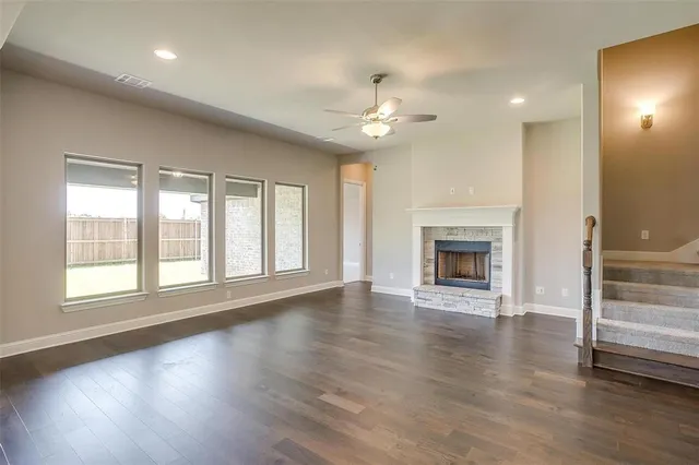 an empty room with wooden floor fireplace and windows