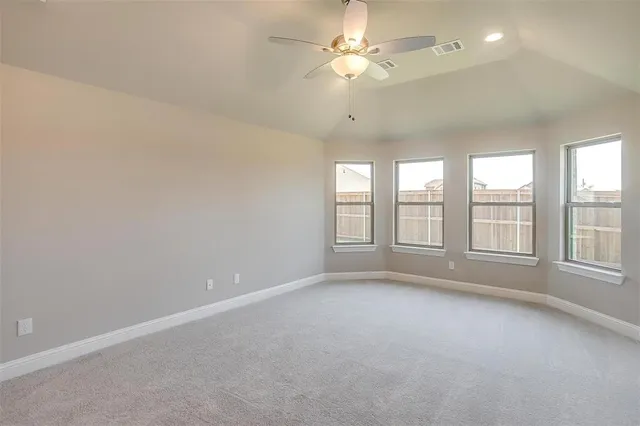 an empty room with chandelier fan and windows