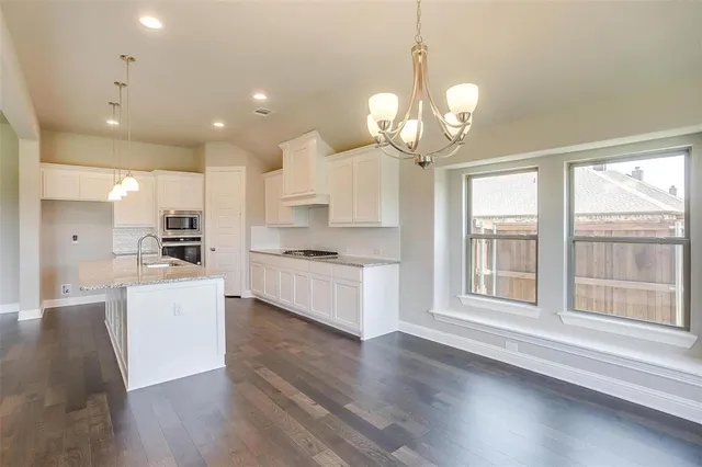 a large white kitchen with lots of counter space wooden floor stainless steel appliances and cabinets