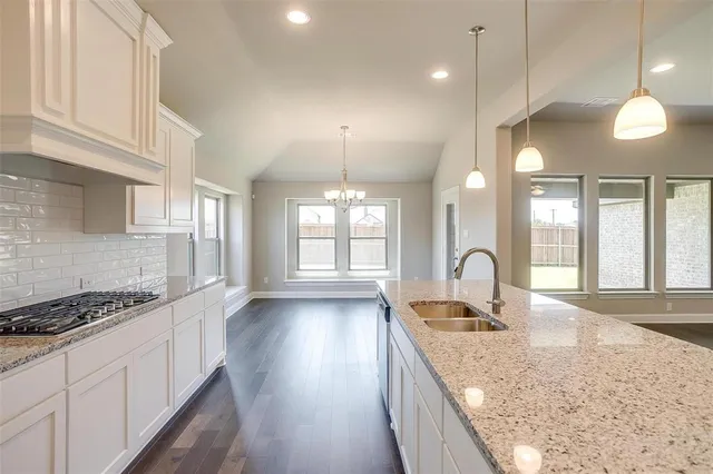 a kitchen with granite countertop a stove a sink a refrigerator and window