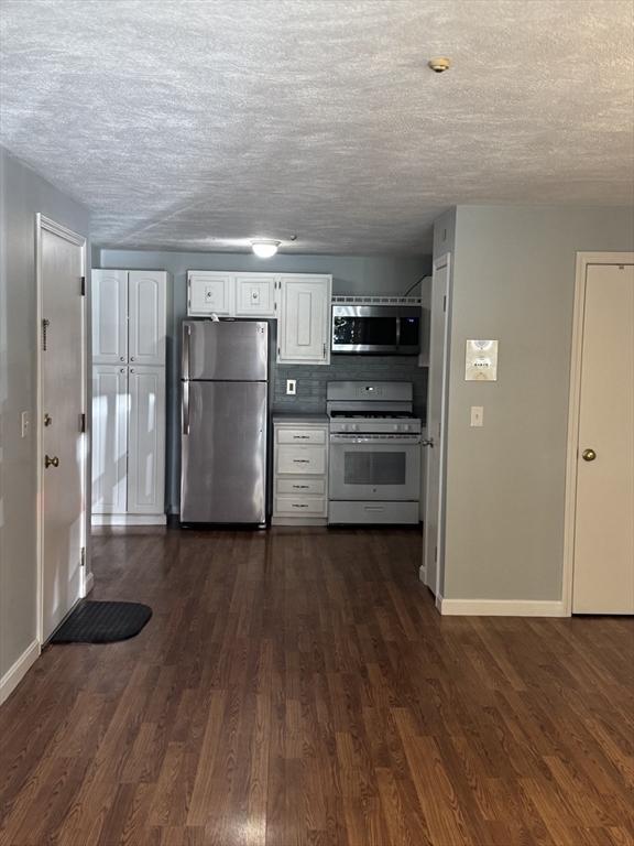 7 Karen Circle, Unit 2 Billerica, MA 01821 - Photo 3 of 11 a view of a refrigerator in kitchen and an empty room with wooden floor