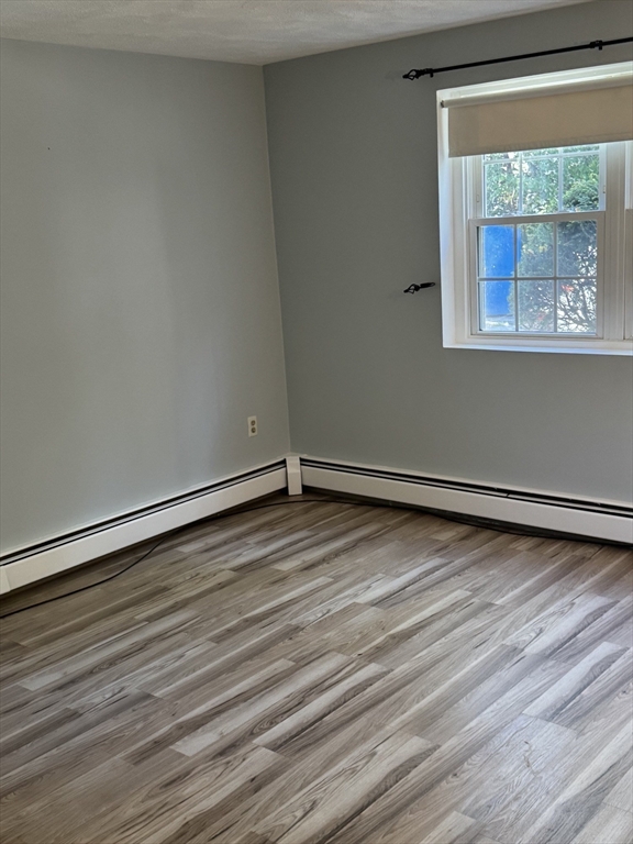 7 Karen Circle, Unit 2 Billerica, MA 01821 - Photo 5 of 11 a view of an empty room with wooden floor and a window