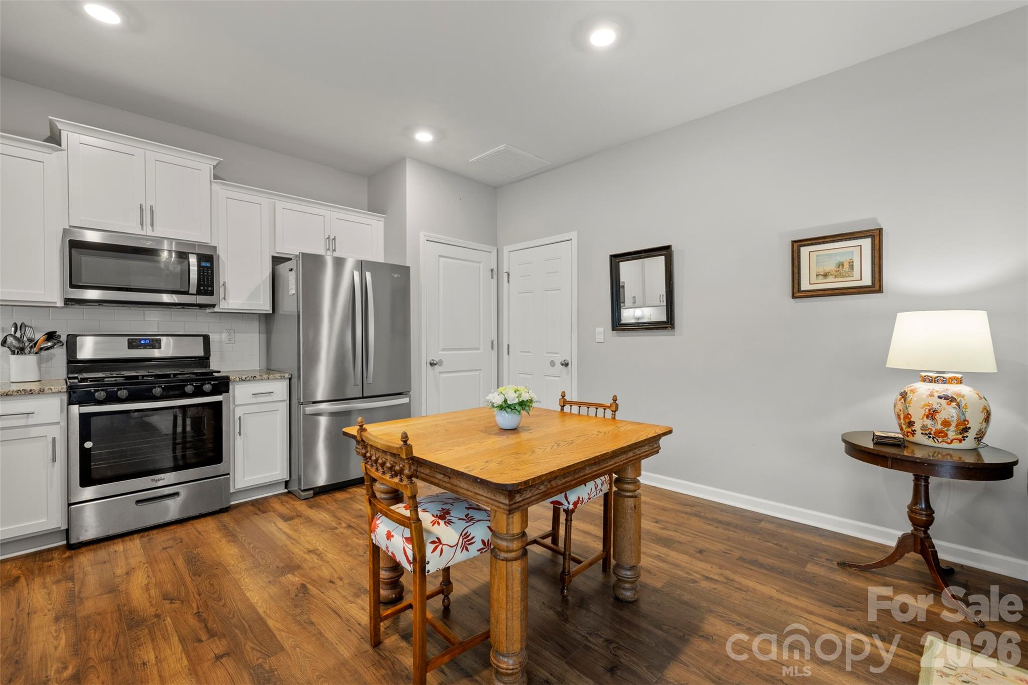 225 Final Stretch Lane Clover, SC 29710 - Photo 18 of 39 a kitchen with stainless steel appliances a stove a refrigerator a sink a dining table and chairs with wooden floor