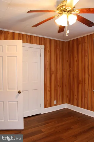 en empty room with wooden floor and fan