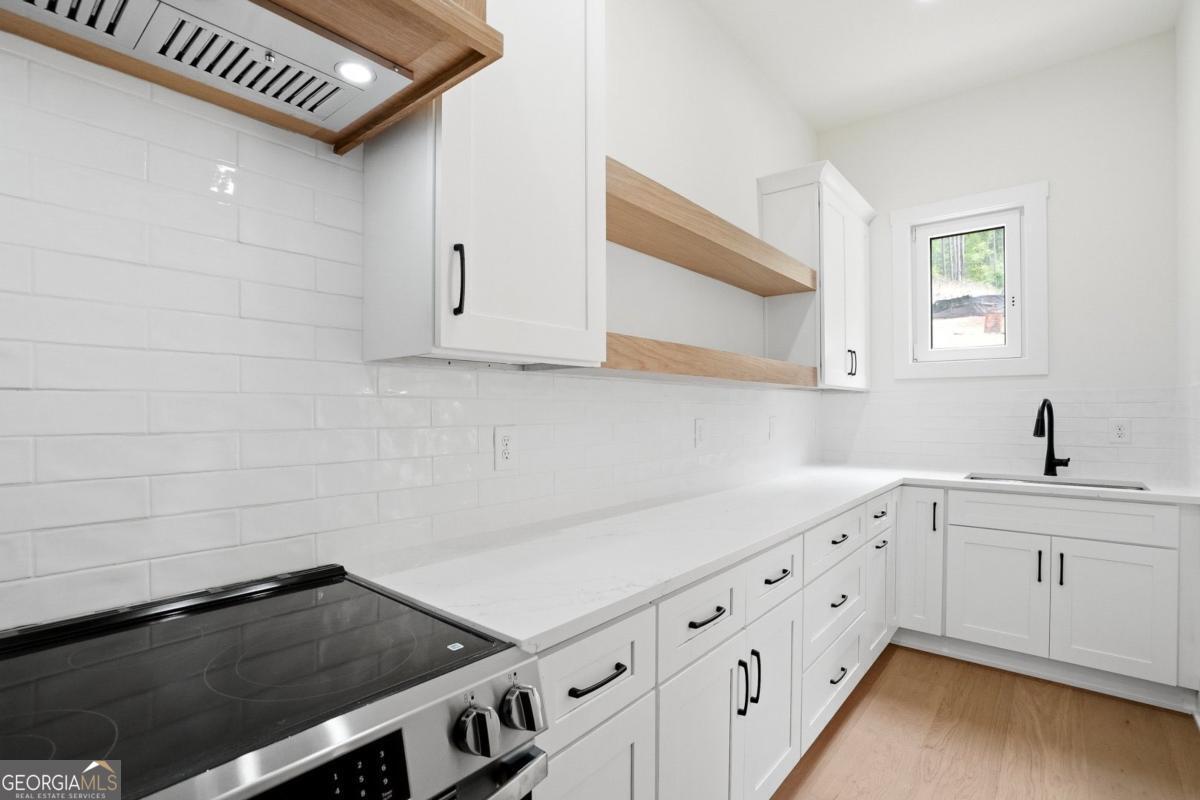 1557 Whitley Road Dacula, GA 30019 - Photo 13 of 46 a kitchen with white cabinets a sink dishwasher and a stove with wooden floor