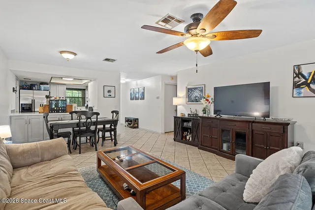 a living room with furniture kitchen view and a wooden floor