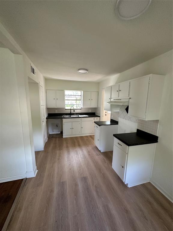 a kitchen with a white cabinets a sink dishwasher and a stove with wooden floor