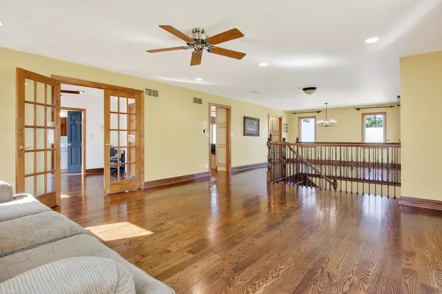 a view of a livingroom with furniture wooden floor ceiling fan and windows