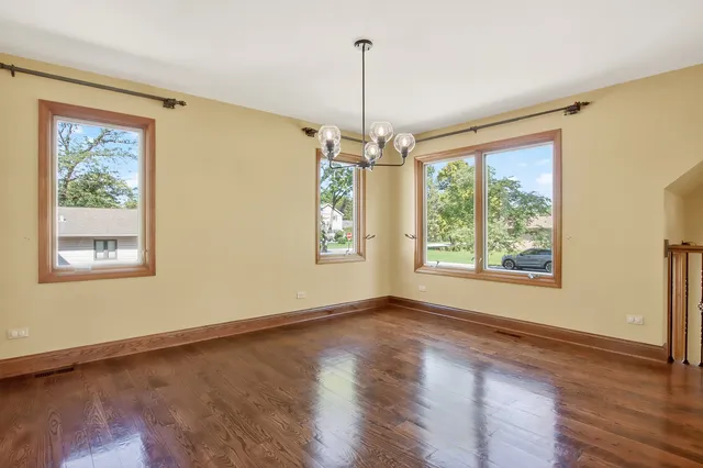 a view of a livingroom with furniture wooden floor chandelier and a window