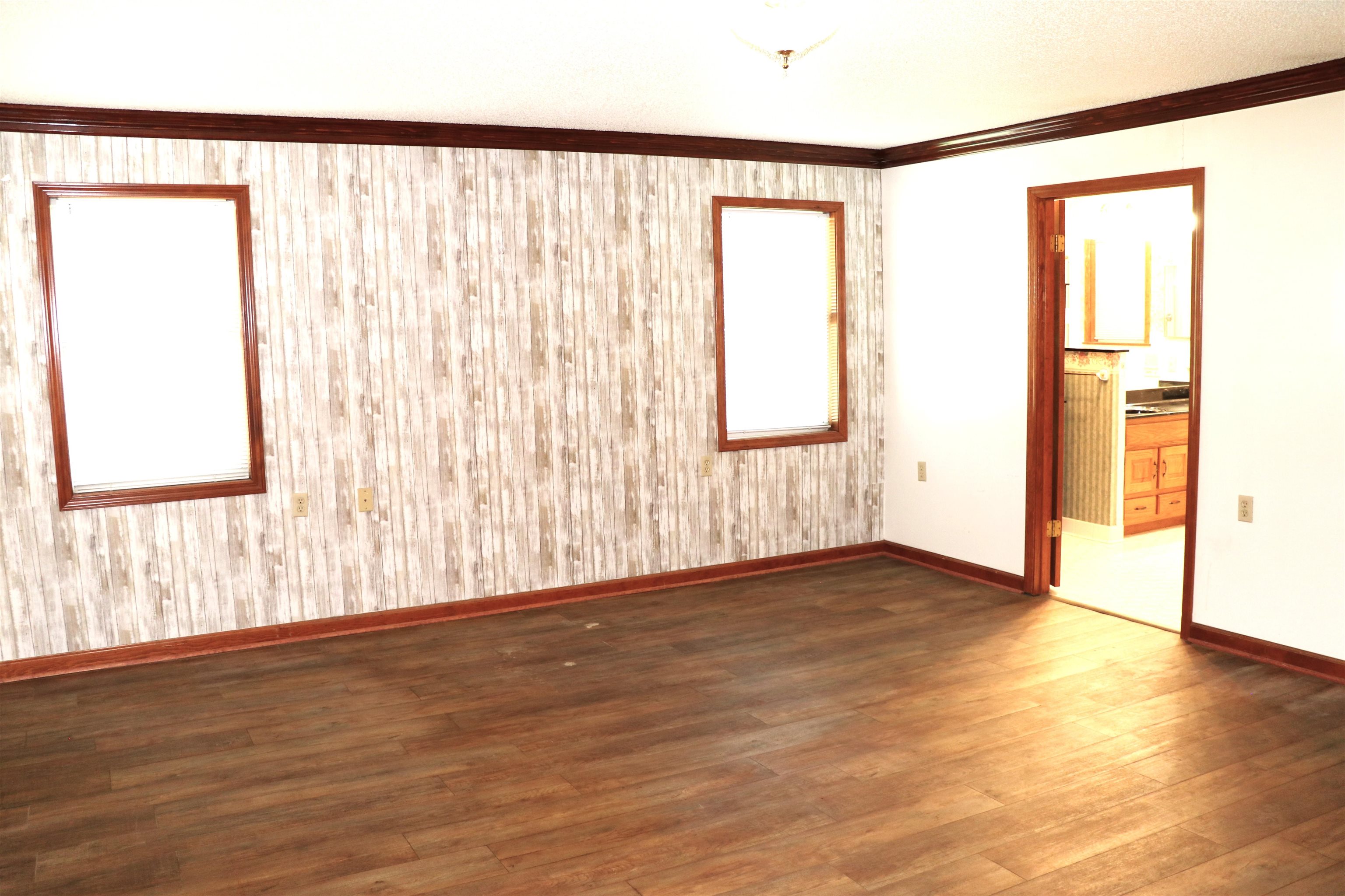 937 Kelleys Chapel Road Burlison, TN 38015 - Photo 13 of 40 Interior room featuring wood-finish flooring, two windows with wood trim, and a patterned accent wall