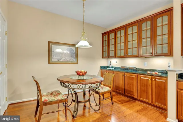 a kitchen with stainless steel appliances granite countertop a stove a sink a dining table and chairs with wooden floor