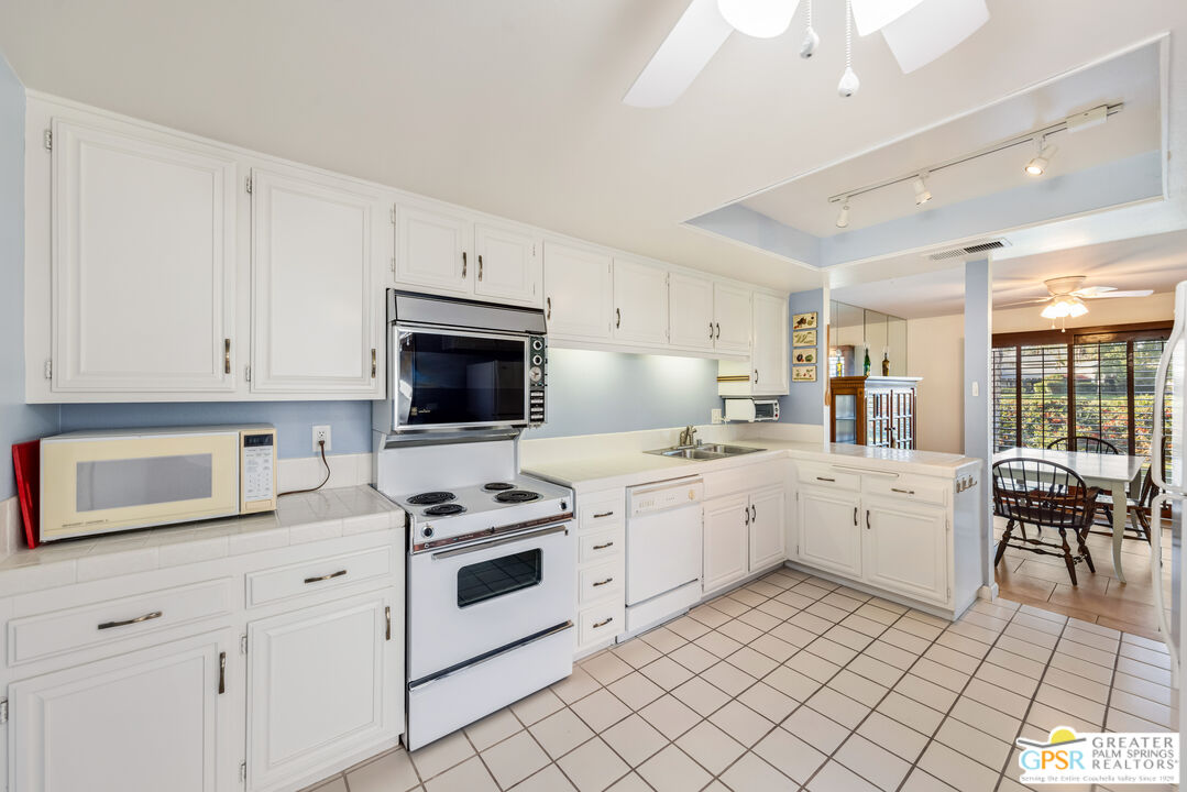 6090 East Driver Road Palm Springs, CA 92264 - Photo 18 of 29 a kitchen with white cabinets and white appliances