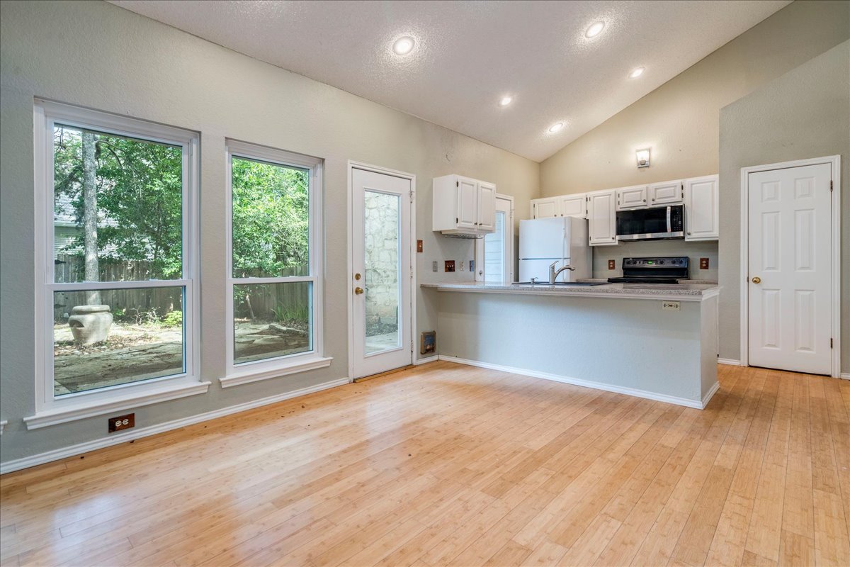 3809 Spicewood Springs Road, Unit 127 Austin, TX 78759 - Photo 7 of 29 Hardwood floors and generous natural light define this welcoming kitchen and dining area.