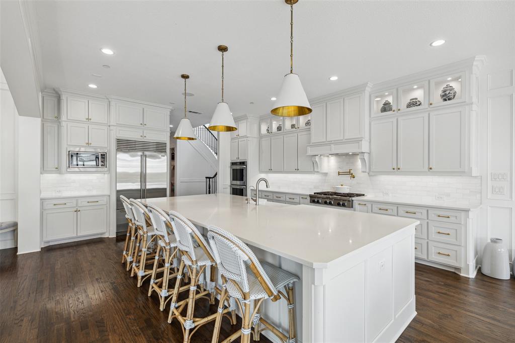 a kitchen with stainless steel appliances a stove a sink a center island and a wooden floor