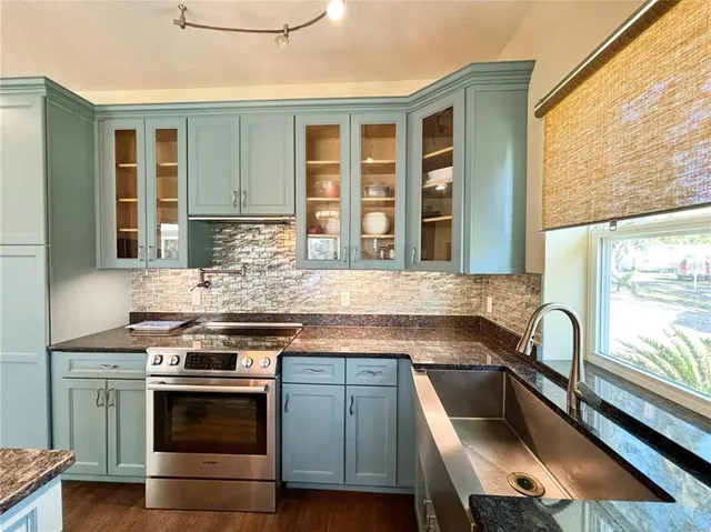 a kitchen with stainless steel appliances wooden floors and white walls