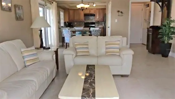 a living room with furniture a chandelier and kitchen view