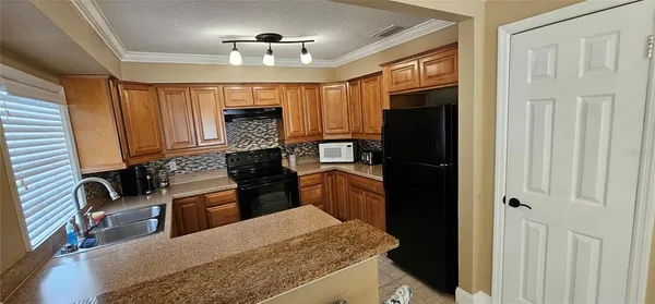 a kitchen with granite countertop wooden cabinets and a refrigerator