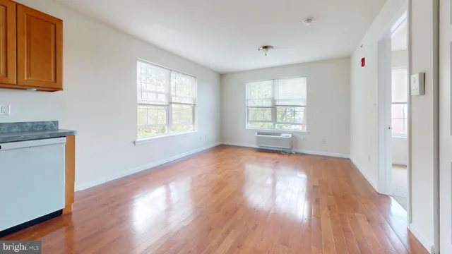 an empty room with wooden floor and windows