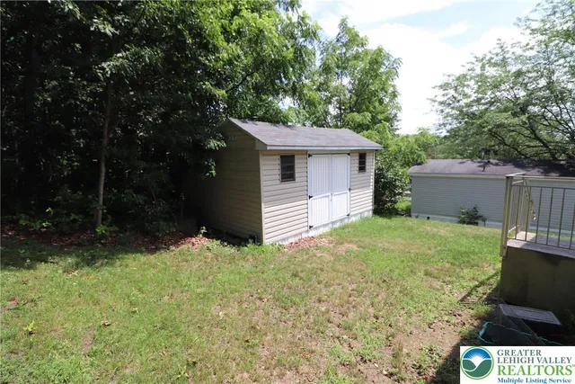 a backyard of a house with plants and large tree
