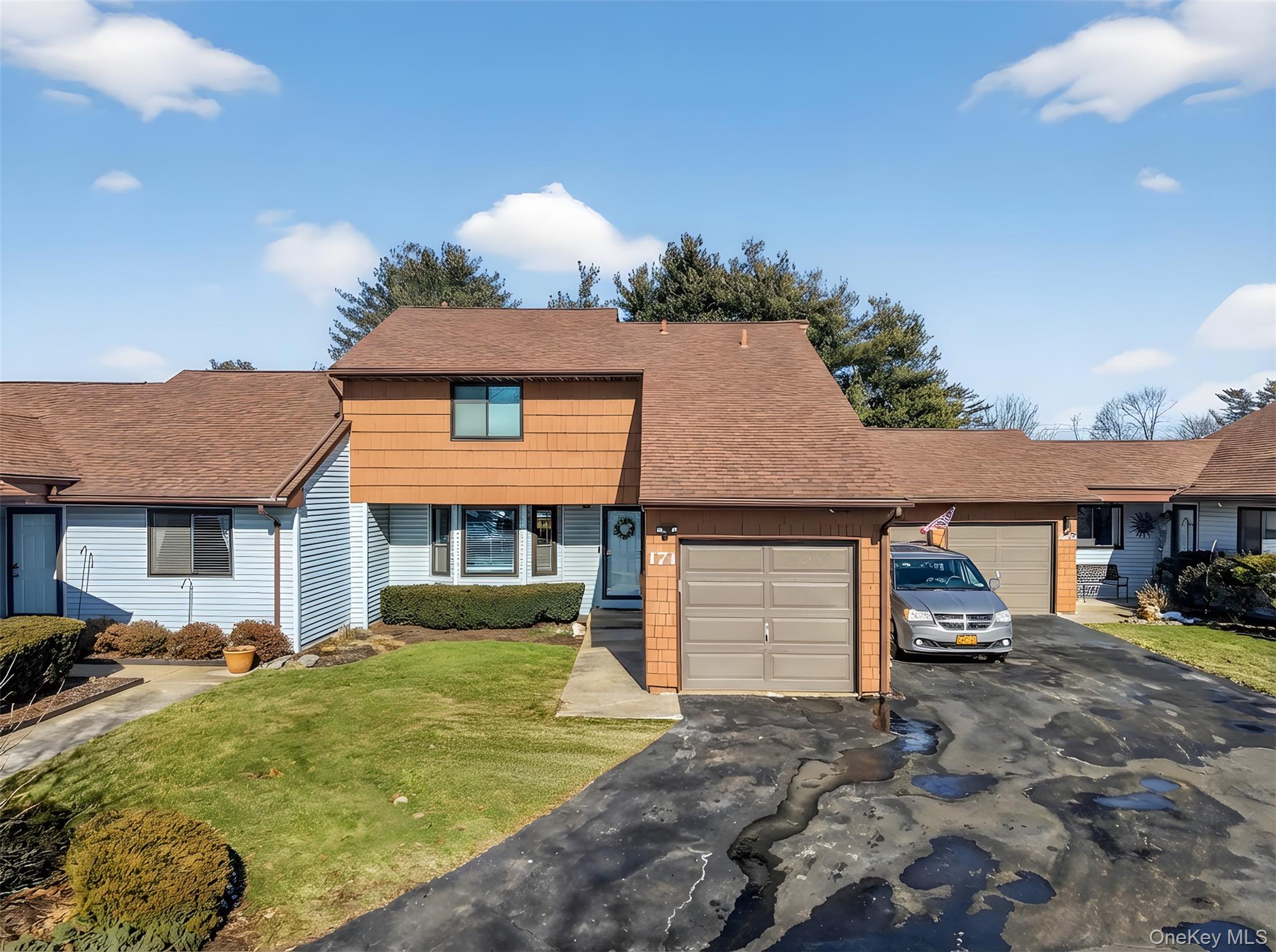 View of front of home featuring a front yard, roof with shingles, driveway, and a garage