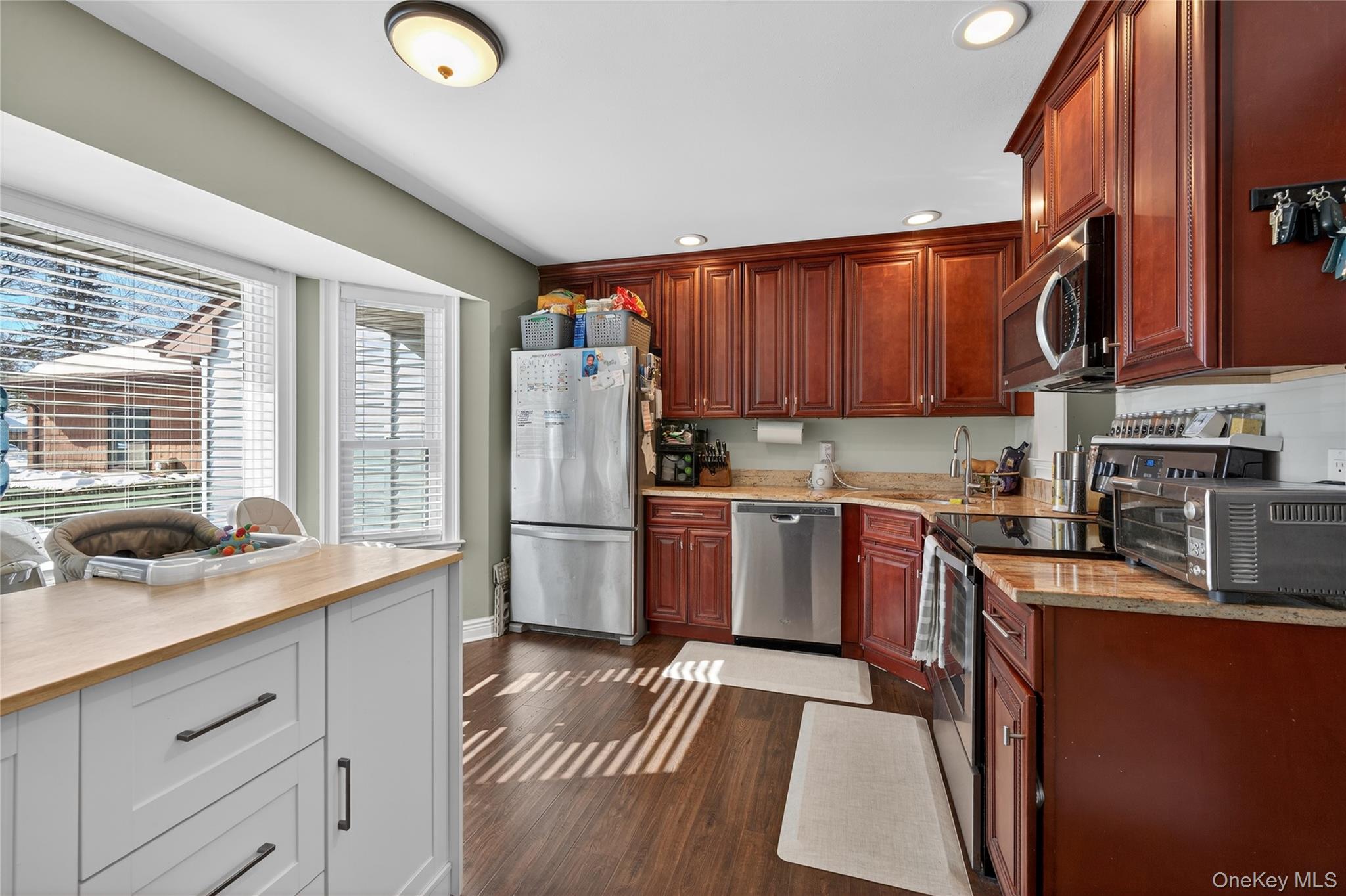 171 Melanie Way Commack, NY 11725 - Photo 15 of 29 Kitchen with stainless steel appliances, recessed lighting, dark wood-type flooring, and light stone countertops