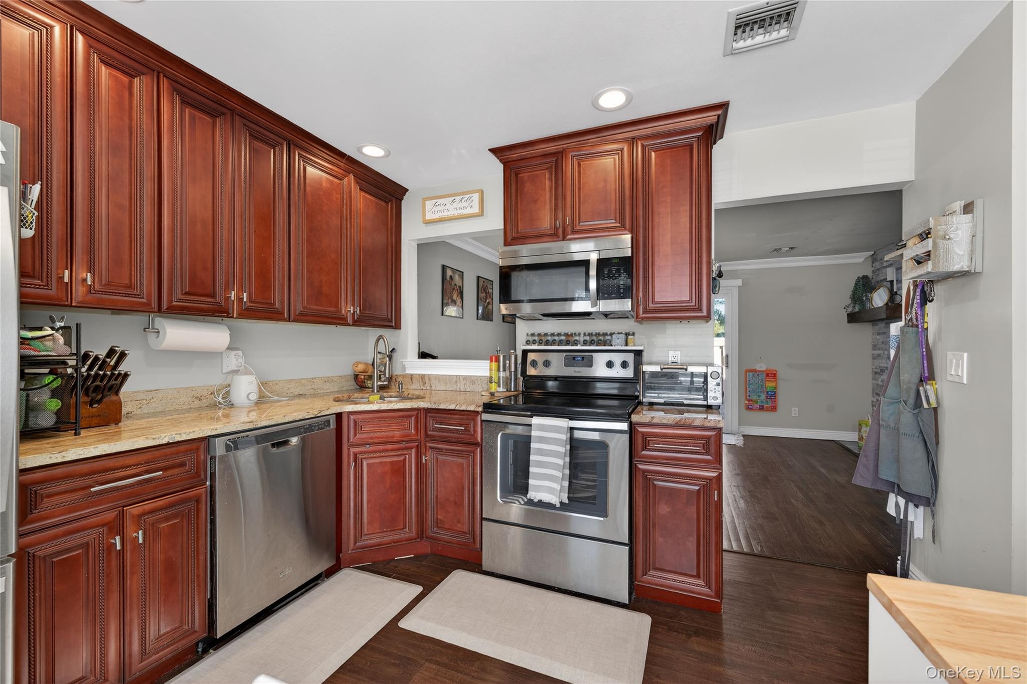 171 Melanie Way Commack, NY 11725 - Photo 16 of 29 Kitchen featuring stainless steel appliances, dark wood-type flooring, recessed lighting, light stone counters, and reddish brown cabinets