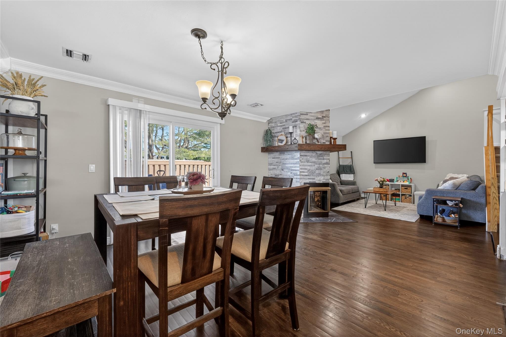 171 Melanie Way Commack, NY 11725 - Photo 17 of 29 Dining room featuring crown molding, dark wood finished floors, suspended lighting, a fireplace, and vaulted ceiling