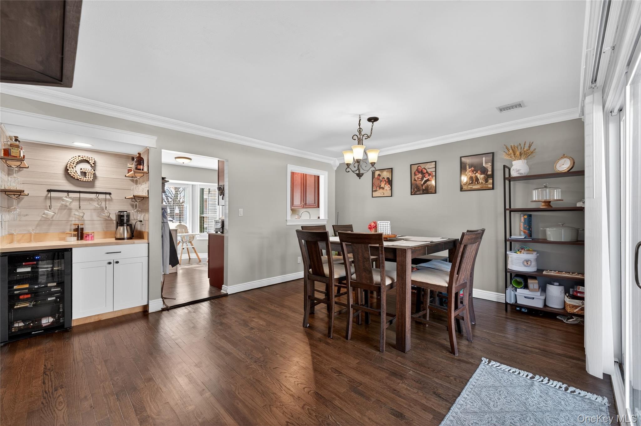 171 Melanie Way Commack, NY 11725 - Photo 18 of 29 Dining space featuring beverage cooler, dark wood-style floors, crown molding, and suspended lighting