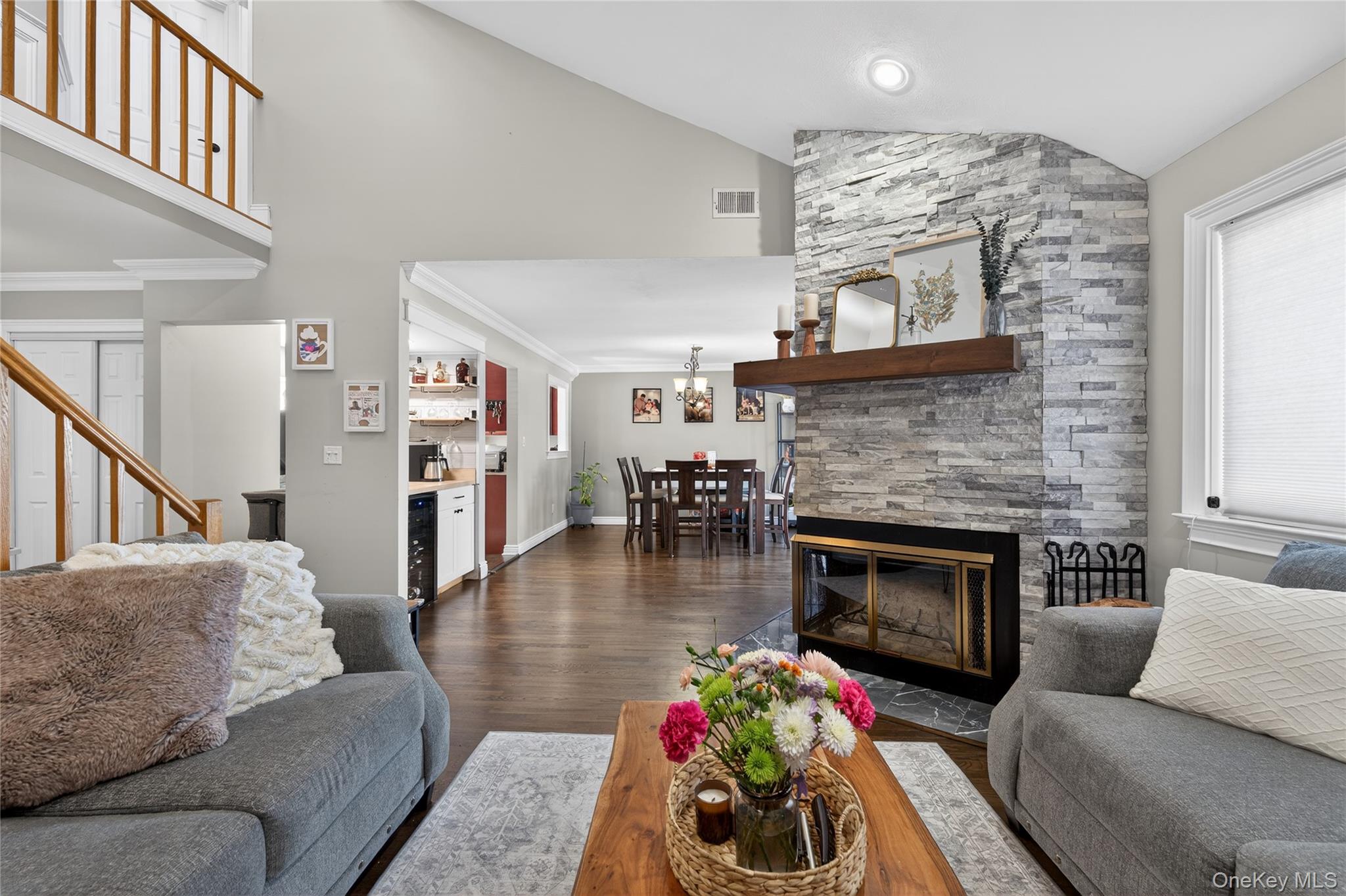 171 Melanie Way Commack, NY 11725 - Photo 19 of 29 Living area with a fireplace, lofted ceiling, dark wood-type flooring, beverage cooler, and a chandelier