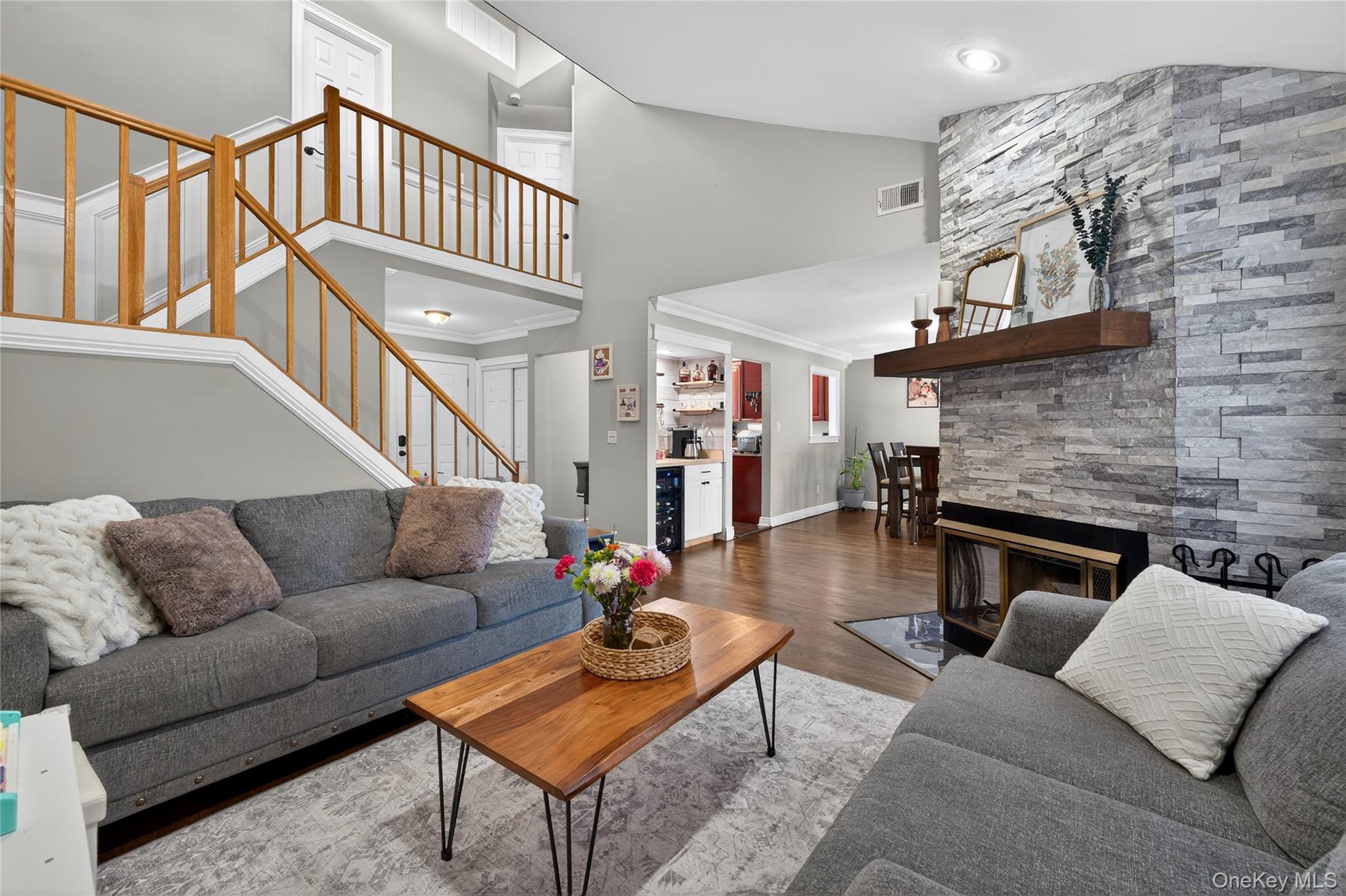 171 Melanie Way Commack, NY 11725 - Photo 2 of 29 Living area featuring wood finished floors, a fireplace, ornamental molding, beverage cooler, and lofted ceiling