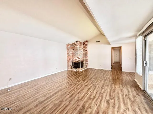 a view of empty room with wooden floor and fireplace
