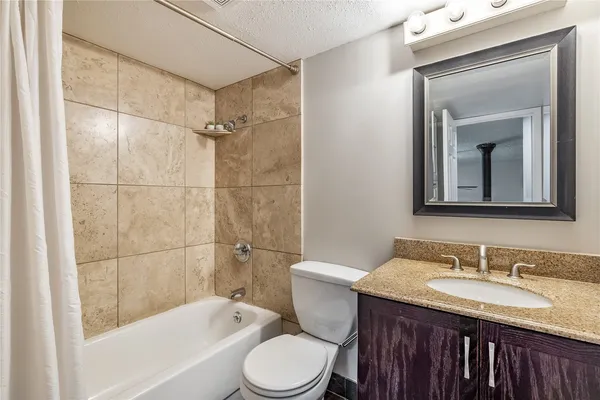 a bathroom with a granite countertop sink toilet and shower