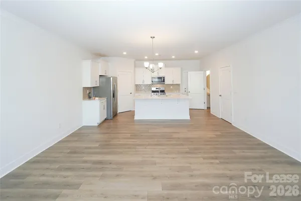 a view of kitchen with kitchen island a sink wooden floor and a refrigerator