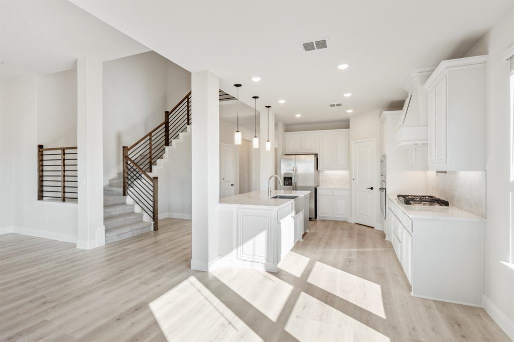 913 Firewood Way Anna, TX 75409 - Photo 16 of 40 a large white kitchen with a refrigerator a sink dishwasher and a stove with wooden floor