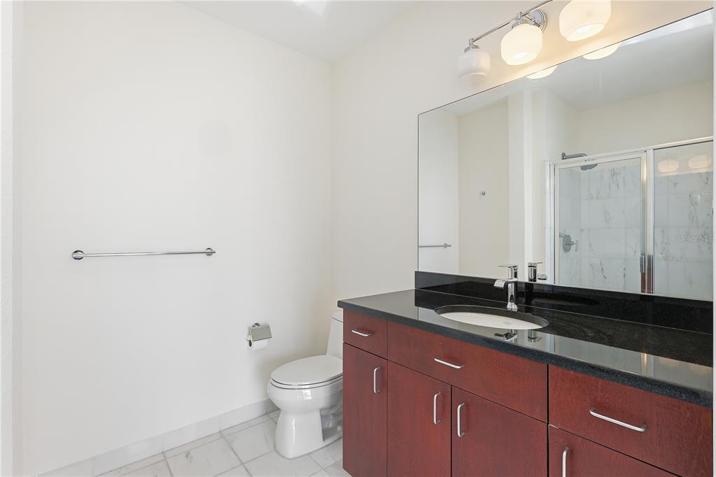 150 East Robinson Street, Unit 2002 Orlando, FL 32801 - Photo 14 of 41 a bathroom with a granite countertop sink a toilet and a mirror