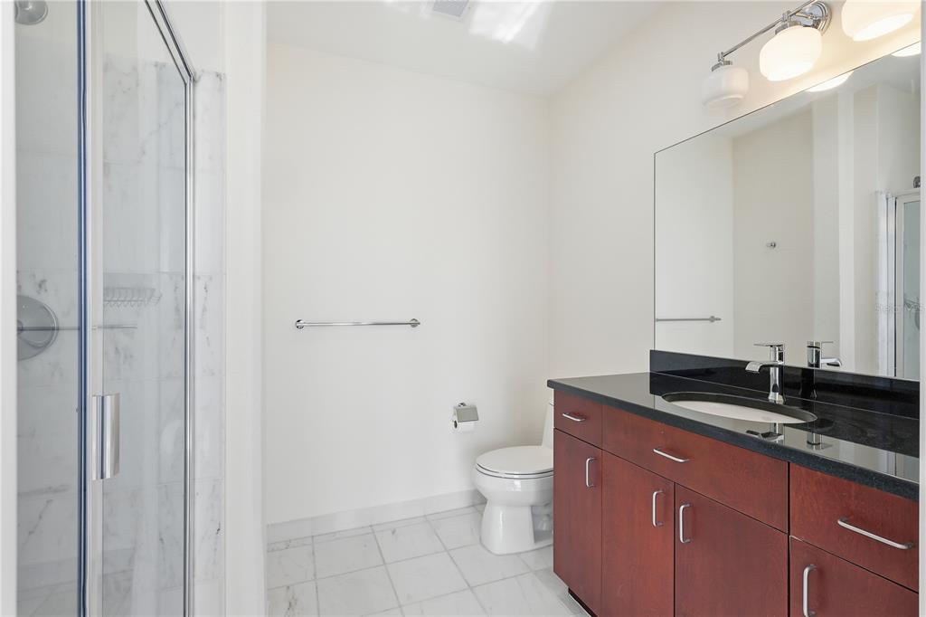 150 East Robinson Street, Unit 2002 Orlando, FL 32801 - Photo 15 of 41 a bathroom with a granite countertop sink a toilet and a mirror