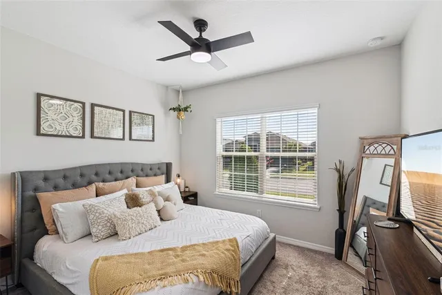 a bedroom with a bed potted plant on the dresser and a chandelier