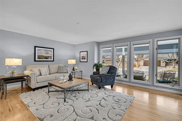 a living room with furniture large windows and wooden floor