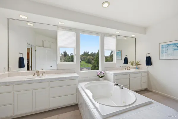 a bathroom with a double vanity sink large mirror and bathtub
