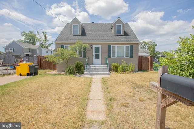 a front view of a house with large trees