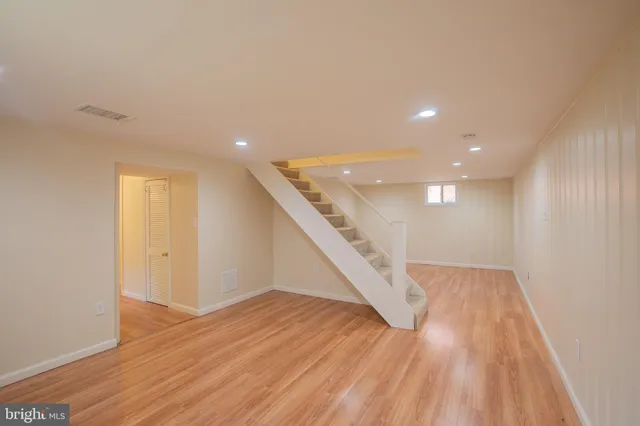 a view of an empty room with wooden floor and stairs